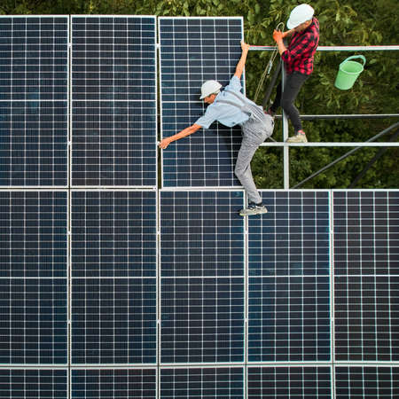 Aerial view of men engineers installing photovoltaic solar panels to high steel platform. Concept of alternative energy.の写真素材