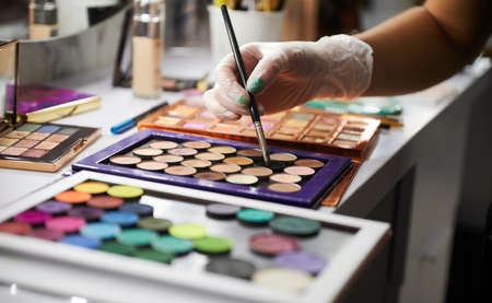 Makeup artist with professional cosmetics in beauty salon. Close up of female hand in sterile gloves...