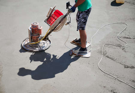 Close up of man builder using troweling machine while screeding floor. Worker finishing concrete...