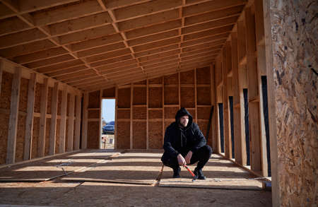 Male engineer building wooden frame house in the Scandinavian style barnhouse. Man developer on...