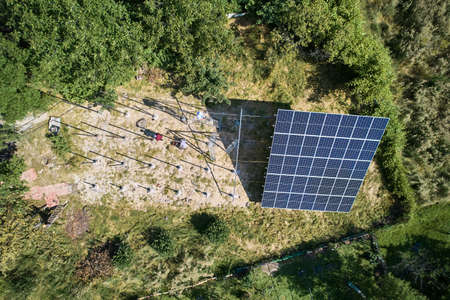 Aerial view of workers installing solar panels to high steel platform in field at sunny day. Concept...