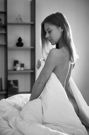 Young naked woman in bed. Black and white image.の写真素材