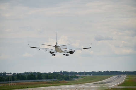 Commercial airplane flying in the sky at cloudy weather. Back view of airliner landing at the airport. Travel concept.の写真素材