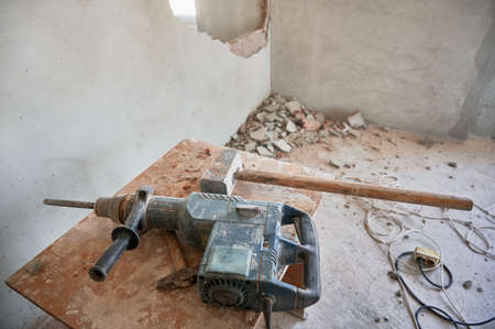 Wooden desk with electric drill, hammer and sledgehammer for construction and demolition works....