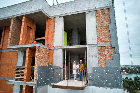 Man with wife and child standing inside residential building under construction. Urban district with...