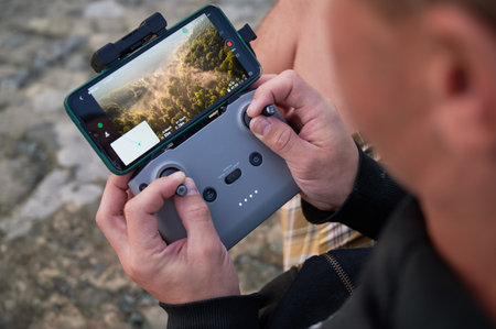 Close up man operating drone using remote controller. Man using drone at sunset for photos and video...