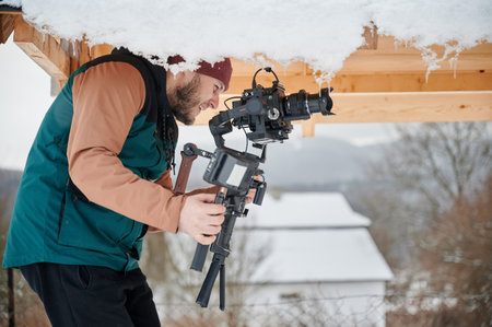 Happy videographer man shooting footage, using camera mounted on gimbal stabilizer equipment in...