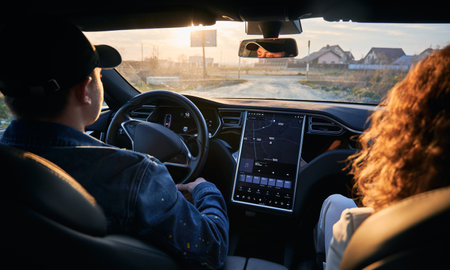 Rear view inside the car. Driver and passenger travelling by electric car with modern user interface...
