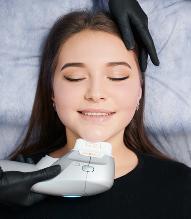 Kyiv, Ukraine - December 26, 2020: young woman lying and beautician doing cleaning face, using Ultraformer. Concept of process procedure for improvements skin in professional beauty salon.のeditorial素材