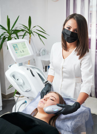 Kyiv, Ukraine - December 26, 2020: Specialist in the field of aesthetic medicine performing ultrasonic non-surgical facelift procedure for woman. SMAS lifting - great alternative to plastic surgery.のeditorial素材