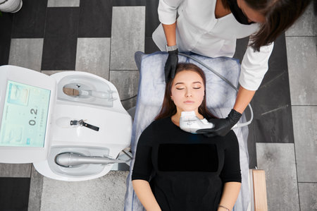 Kyiv, Ukraine - December 26, 2020: Top view of process of ultrasonic SMAS-facelift by Ultraformer. Patient lying on couch in office for medical procedures in hardware cosmetology.のeditorial素材