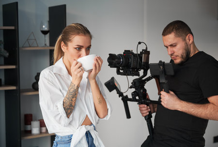 Videographer man shooting footage with female model, using camera mounted on gimbal stabilizer...