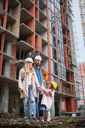 Happy family homeowners standing on the street at construction site.