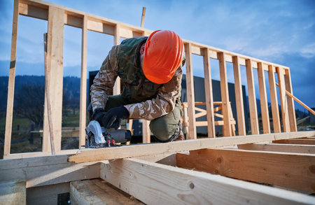 Carpenter using circular saw for cutting wooden plank. Man worker building wooden frame house. Carpentry concept.の写真素材