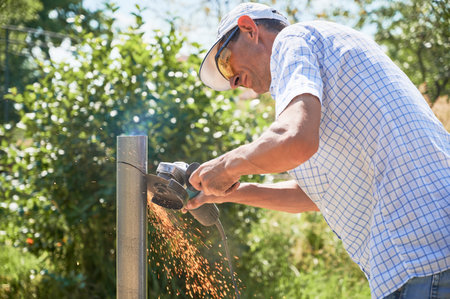 Worker cutting metal pole with grinder for installing solar panels.の写真素材