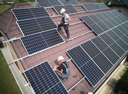 Men technicians building photovoltaic solar moduls on roof of house. Engineers in helmet installing solar panel system outdoors. Concept of alternative and renewable energy. Aerial view.の写真素材