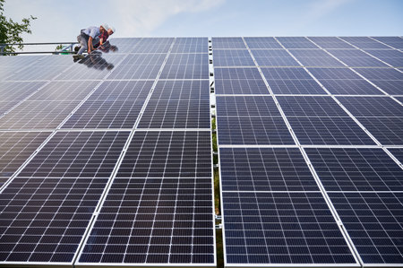 Male workers mounting photovoltaic solar panel system outdoors. Men electricians placing solar module on metal rails. Renewable and ecological energy.の写真素材