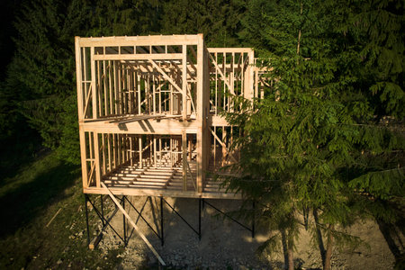 Drones vantage point offers view of two-storey wooden-framed domicile in process of construction near forest. Idea of contemporary ecological construction and modern architectural design.の写真素材