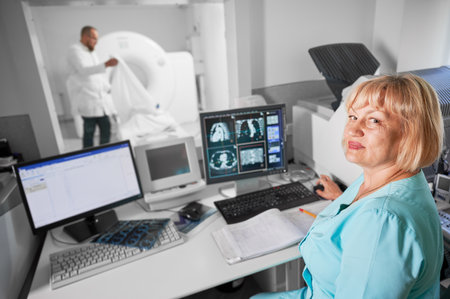 Medical computed tomography or MRI scanner. Portrait of female nurse working at computer, making MRI. Woman wearing blue uniform. Concept of medicine and hospital.の写真素材
