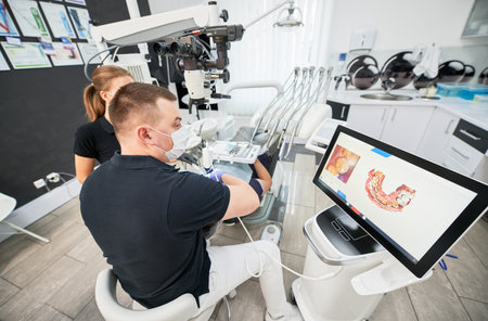 Dentist scanning patients teeth with modern machine for intraoral scanning. Digital print of patients teeth is on big screen. Modern high precision technologies. Concept of modern dentistryの写真素材