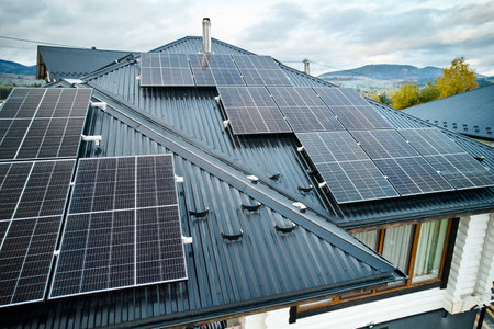 Photovoltaic solar panel system on the roof of house. Modern solar modules installed on house. Concept of alternative, renewable energy and home autonomy.の写真素材