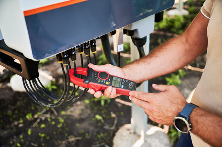 Inspector checking output voltage level of inverter. Professional worker using current clamps to know how solar panel working. Techinician service of PV battery.の写真素材