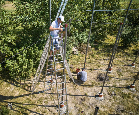 Worker standing on staircase and cutting metal beam with grinder for installing solar panels. Ground-mounted photovoltaic systems. Solar modules are held in place by racks or frames.の写真素材