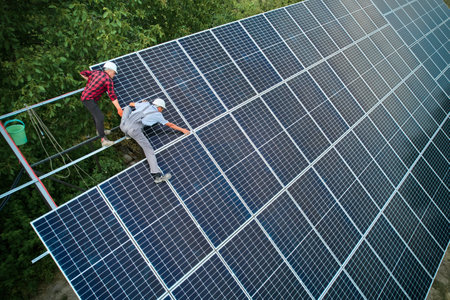 Aerial view of men technicians installing photovoltaic solar panels to high steel platform. Concept of alternative energy.の写真素材