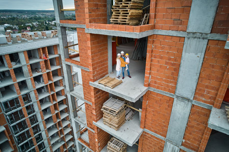 Man with wife and child standing inside residential building under construction. Urban district with newly constructed apartment building and family new residents real estate buyers. Drone viewの写真素材