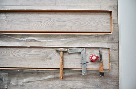 Metal construction ruler, hammer and measuring tape on laminate wood plank. Building repair tools and instruments for laminate flooring installation, construction works and home renovation.の写真素材