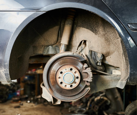 Close up of worker changing car wheel in garage, auto servicing center. Automobile being repaired, maintained by mechanics, repairmen, technicians. Concept of fixing car.の写真素材
