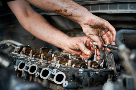 Close up of mechanic repairing car engine, working in garage, workshop, auto servicing center. Worker, repairman holding screwdriver. Concept of fixing car.の写真素材