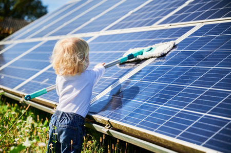 Little kid learning how to clean solar panel. Young boy learning how to care about solar station. Concept of young generation and green energetic.の写真素材
