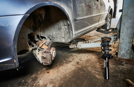 Close up of repairman, worker changing car wheel. Mechanic repairing car in garage, auto servicing center, fixing problem. Concept of manual work and repairing automobiles.の写真素材