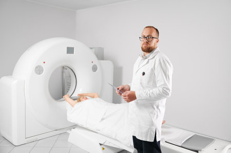 Medical computed tomography or MRI scanner. Portrait of doctor holding and examining results of MRI. Woman patient lying on couchette. Concept of medicine, healthcare and modern diagnostics.の写真素材