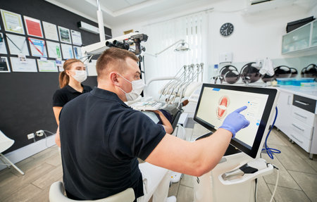 Dentist scanning patients teeth with modern machine for intraoral scanning. Digital print of patients teeth is on big screen. Modern high precision technologies. Concept of modern dentistryの写真素材