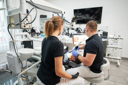 Dentist scanning patients teeth with modern machine for intraoral scanning. Digital print of patients teeth is on big screen. Modern high precision technologies. Concept of modern dentistryの写真素材