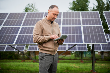Male investor counting his future income from alternative energy investment. Confident man investing in green energy sources. Man calculating profit from his solar panels.の写真素材