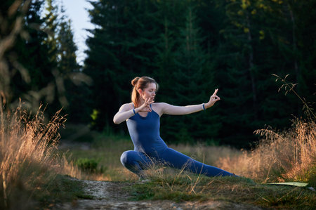 Sporty woman practicing yoga in forest. Middle-aged woman exercising early in morning. Female doing sport outdoor.の写真素材