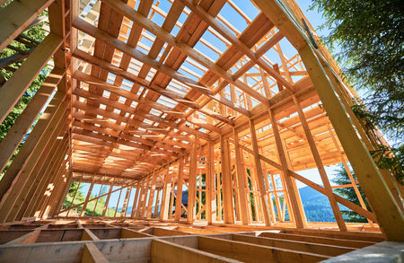 Under-construction residential wooden frame home located near a forest. Commencement of a new construction project for a cozy house or a mountain cottage. Idea of contemporary ecological construction.の写真素材