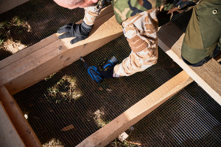Male builder working with screwdriver inside of future cottage. Man worker building wooden frame house. Carpentry and construction concept.の写真素材