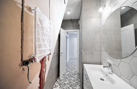 Apartment bathroom with electric towel dryer before and after restoration. Old flat and new renovated bathroom with sink and mirror.の写真素材