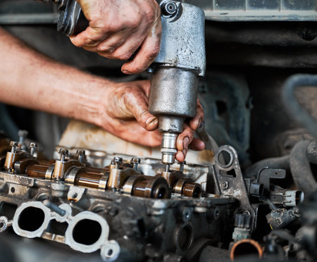 Close up of worker mechanic repairing, fixing car engine. Repairman working in garage, workshop, auto servicing center, twisting off engine. Concept of servicing autos.の写真素材