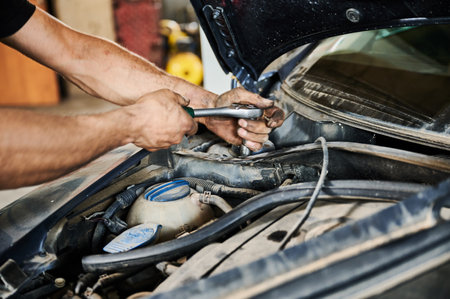 Close up of enginner, mechanic holding screwdriver, repairing, fixing car. Strong, hardworking man working in auto, service center, garage. Concept of manual labor.の写真素材