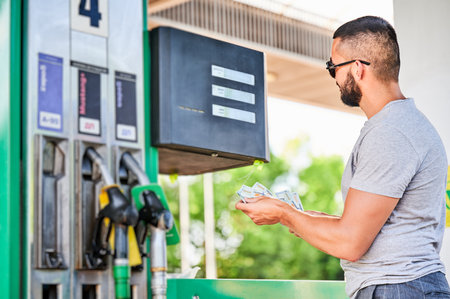 Worried man shocked how much gasoline costs. Driver counting if he has enough money to pay for fuel. Transportation expenses concept.の写真素材