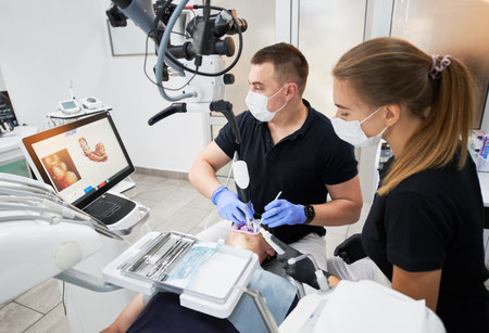 Dentist scanning patients teeth with modern machine for intraoral scanning. Digital print of patients teeth is on big screen. Modern high precision technologies. Concept of modern dentistryの写真素材