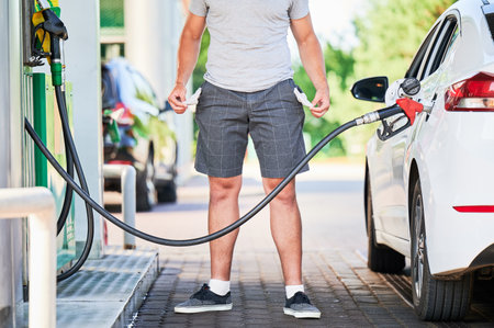 Man left with empty pockets after spending all money on fuel. Cropped view of man showing that he has no money after refueling his car. High fuel prices concept.の写真素材