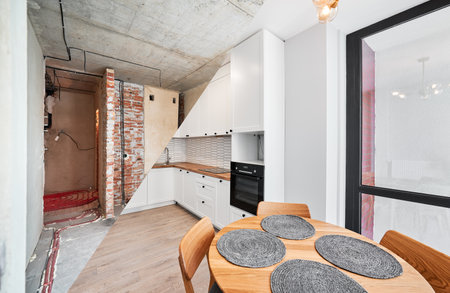 Modern apartment before and after restoration or refurbishment. Comparison of old kitchen room and new place with parquet floor, table, kitchen counter, stove and white walls. Home renovation concept.の写真素材