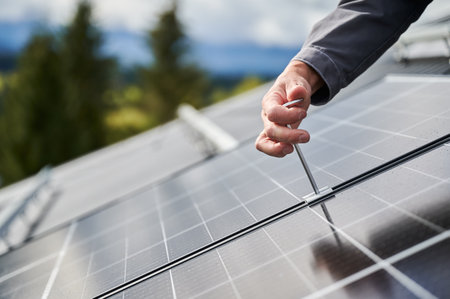 Man worker mounting photovoltaic solar panels on roof of house. Close up view of engineer installing solar module system with help of hex key. Concept of alternative, renewable energy.の写真素材