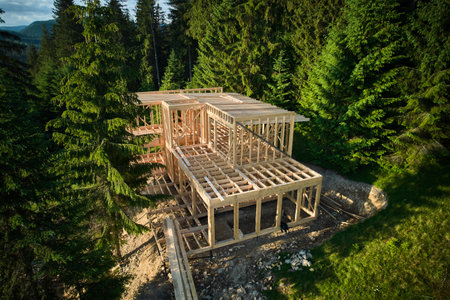 Drone view of two-story wooden frame house under construction near forest. Idea of modern ecological construction and contemporary architectural design.の写真素材